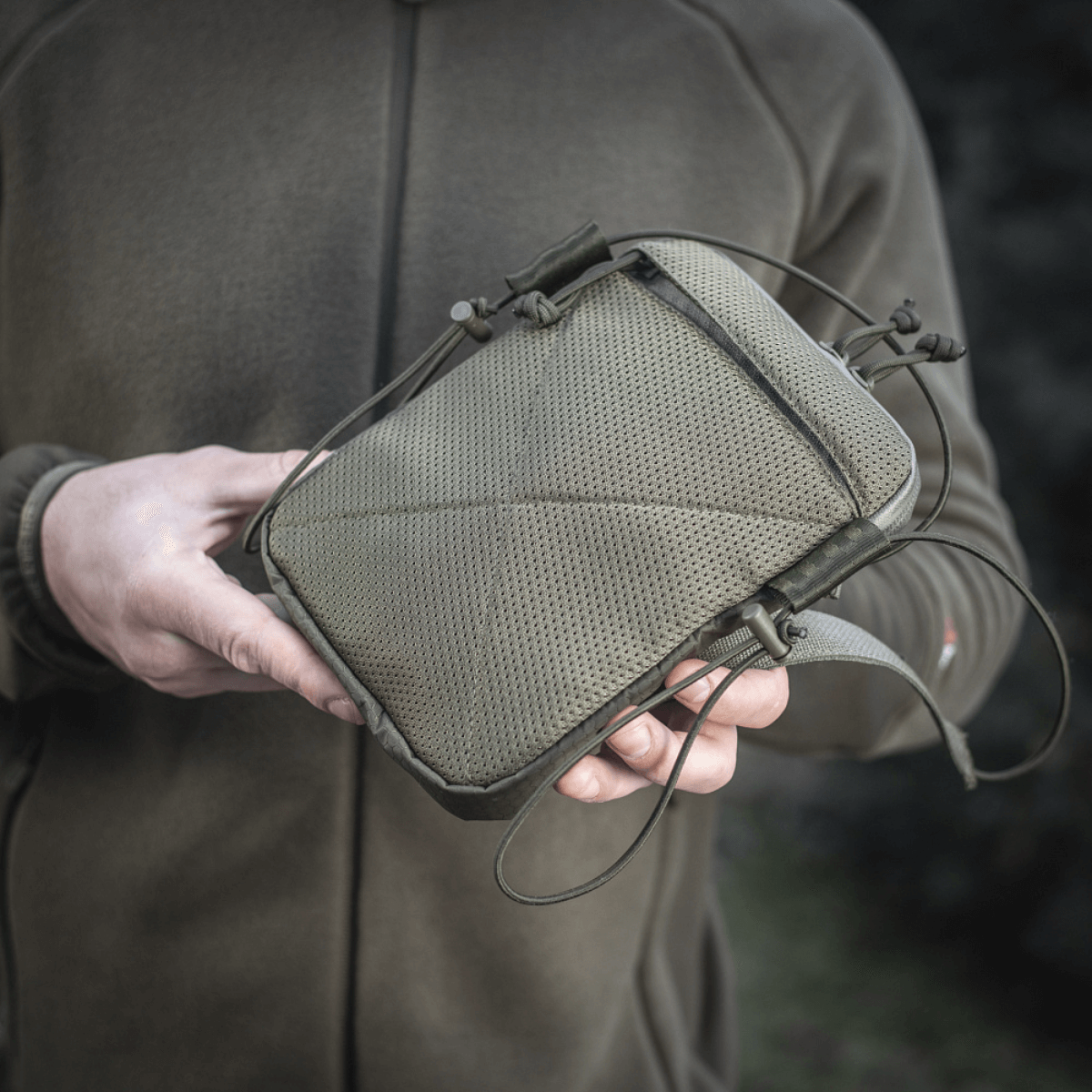 Person holder M‑Tac Pocket Bag Elite HEX, en kompakt, slidstærk taske perfekt til opbevaring af daglige småting og udstyr.