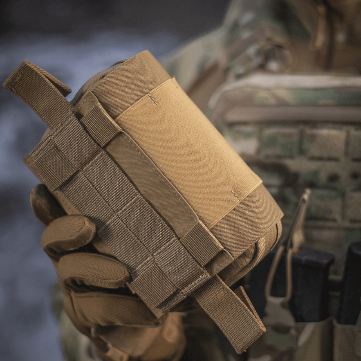 M-Tac Horisontal Medic Lomme Large Elite i corduramateriale, holdt i hånd af person iført uniform. Ideel til førstehjælp på felten.