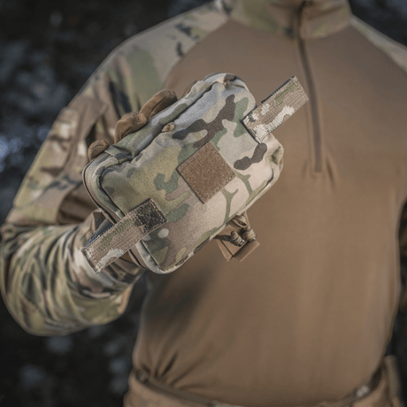 M-Tac Horisontal Medic Lomme Large Elite multicam-materiaalissa, NIJ-sertifiointi, galleria-asento 1, käsissä taktisen varustuksen kanssa.