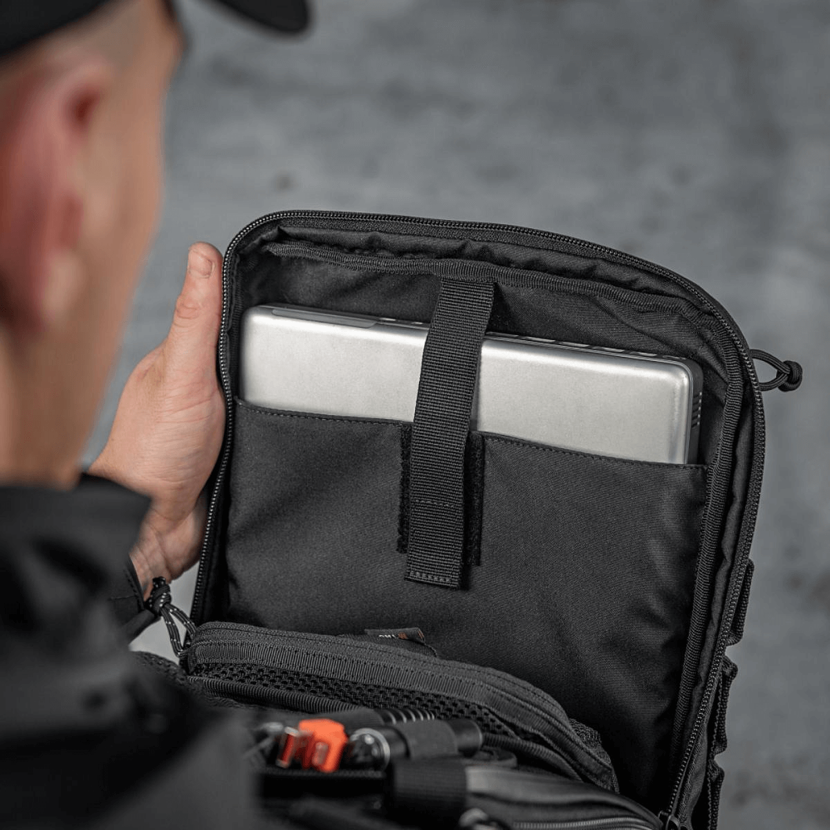 Person åbner M-Tac Tablet Bag Laser Cut Hex med tablet indeni, viser rum til hurtig adgang og dokumenter.