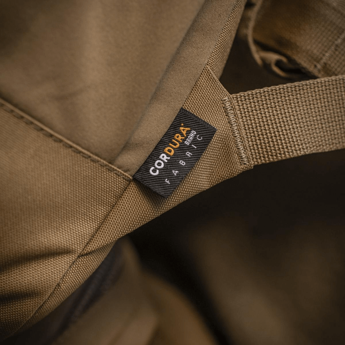 Nærbillede af M-Tac STURM Elite Rygsæk med Cordura stofmærke, der viser høj kvalitet og slidstyrke i designet.