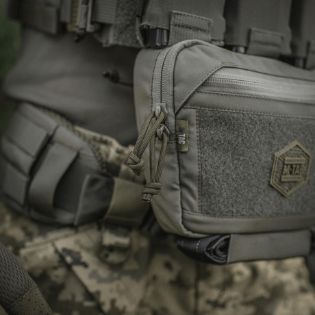 M-Tac Large Elite Gen.II Skuldertaske i Cordura 500D med YKK lynlåse, ideel til taktisk brug, set på camouflage baggrund.