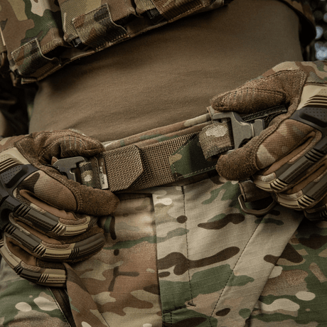M-Tac Cobra Buckle Taktisk Bælte Laser Cut i brug, bæres af en person i camouflage tøj og handsker.