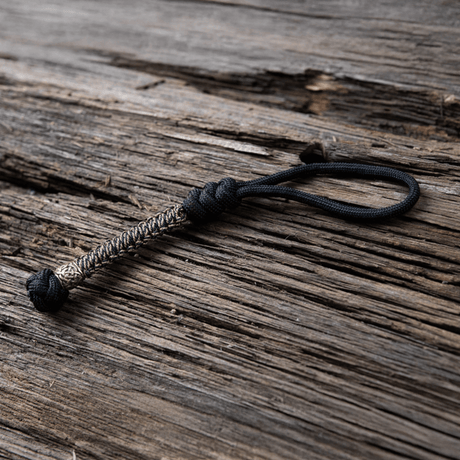 M-Tac Knife Lanyard Scandinavian punottu paracord, tyylikäs ja käytännöllinen lisä taskuveitsille, puutaustalla.