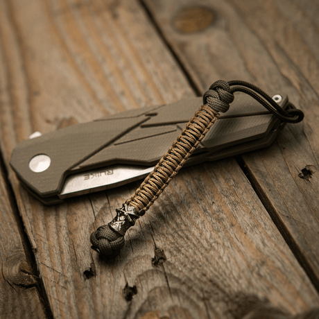 M-Tac Knife Lanyard Ninja paracord taittoveitsen vieressä puupöydällä