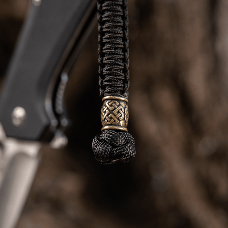 M-Tac Knife Lanyard Celtic, punottu paracord koristeellisella kuviolla, esillä veitsessä tyylikkäänä ja käytännöllisenä lisänä.