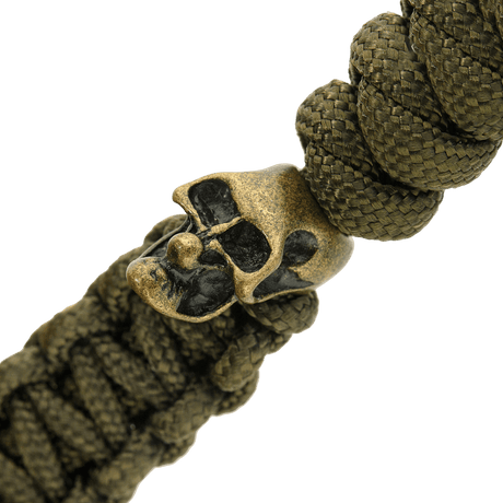 Yksityiskohta oliivinvihreästä M-Tac Loopy Snake Skull Lanyardista, punottu paracord ja koristeellinen metallinen pääkallo, veitselle ja varusteille.