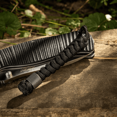M-Tac Viper Lanyard Stainless Steel, punottu paracord ja Viper-helmi, tyylikäs veitsen lisä — musta lanyard puustaustalla.