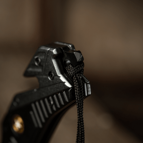 Yksityiskohtakuva M-Tac Zeus Lanyardista, punottu paracord nopeaan käyttöön ja tyylikkääseen ulkonäköön, kiinnitetty veitsen kahvaan.