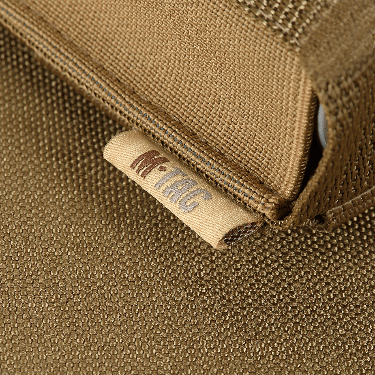 Detalje af M-Tac Gasdåseholder Vertikal med MIL-SPEC strop i brun stofmateriale og mærket logo.