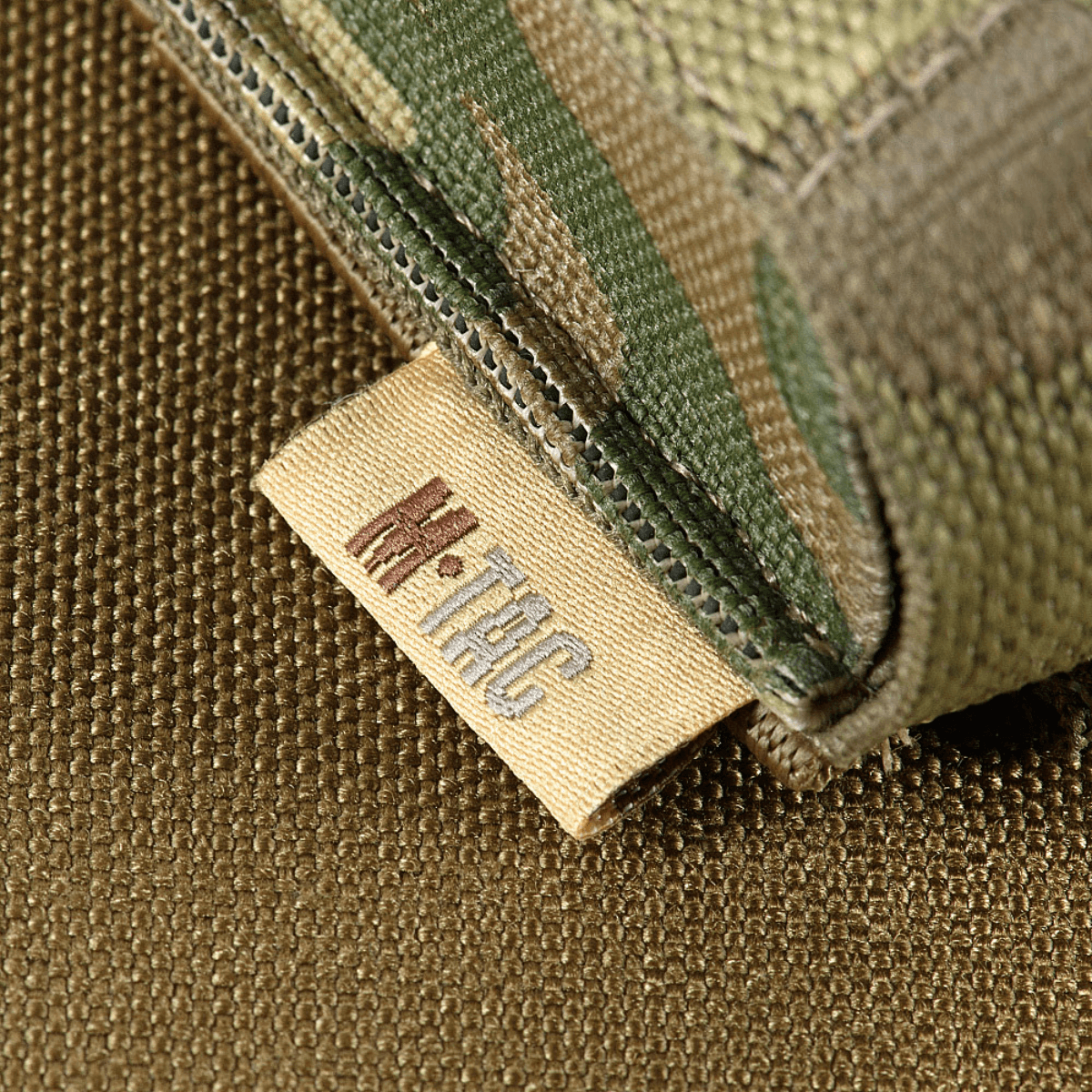 M-Tac Gasdåseholder Vertikal med MIL-SPEC strop og Woojin-lås i camouflage-design, set mod en struktureret baggrund.