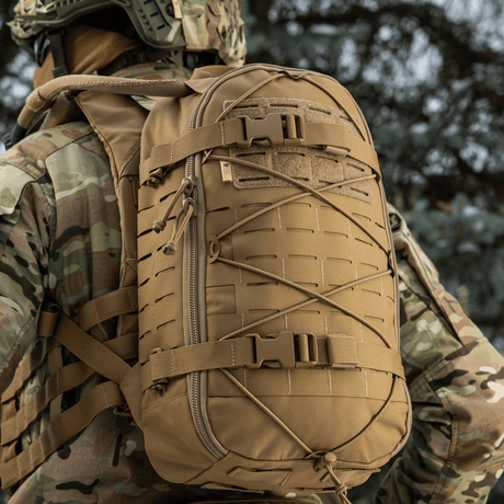 M-Tac reppu Sturm Elite Gen.II MOLLE-järjestelmällä ja joustonarulla, kenttäkäyttöön, kuvattu sotilaalla maastokuvioissa.
