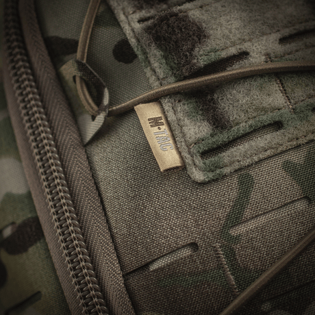 Yksityiskohtainen näkymä M-Tac reppu Sturm Elite Gen.II, valmistettu tukevasta Cordura-materiaalista maastokuvioinnilla ja vetoketjukiinnityksellä.