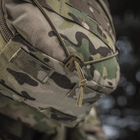 Lähikuva M-Tac reppu Sturm Elite Gen.II maastokuvioinnilla ja bungee-joustonarulla ulkovarusteille.