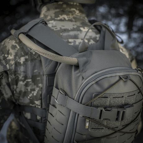 M-Tac Sturm Elite Gen.II harmaasta Cordurasta sotilaan päällä, näyttää sisäänrakennetun juomajärjestelmän letkun luonnossa.