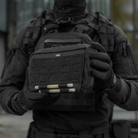 M-Tac Admin Pouch Large Elite mustana, pidetään henkilön toimesta taktisten vaatteiden yllä, valmistettu Cordura 500D:stä.