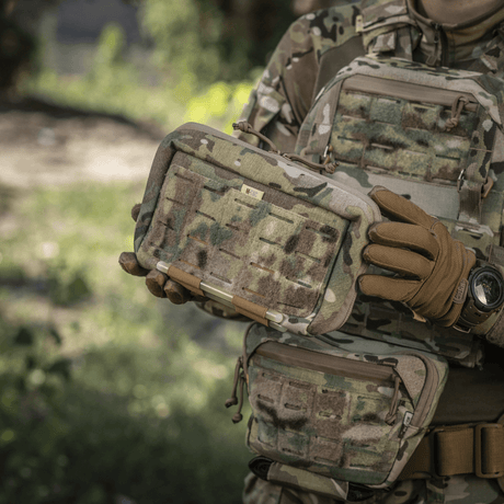 M-Tac Admin Pouch Large Elite kamuflaasiasuiseen henkilöön tarttuneena, näyttää kestävän ja toiminnallisen muotoilun taktiseen käyttöön velcro-paneeleilla.