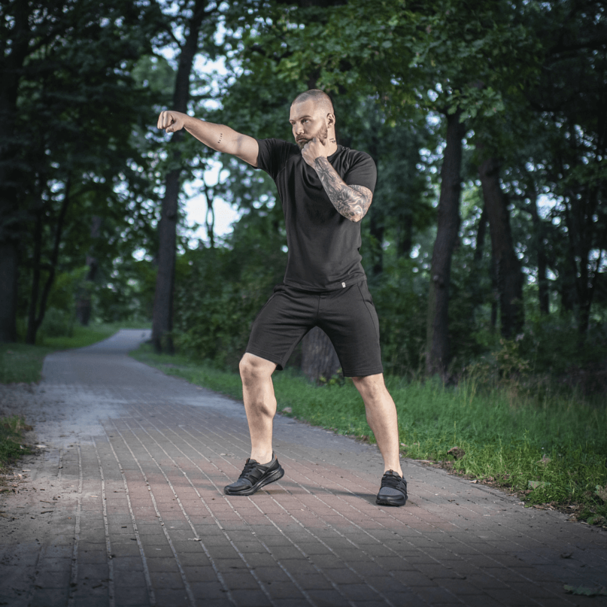Mand i skov iført M-Tac Shorts Casual Fit Cotton, viser bevægelighed og stilrent design på en sti omringet af træer i naturen.