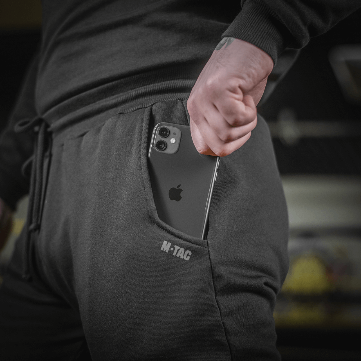 Person iført M-Tac Bukser Cotton Classic med smartphone i sidelomme, sportstøj i 100% bomuld med komfort og bevægelsesfrihed.