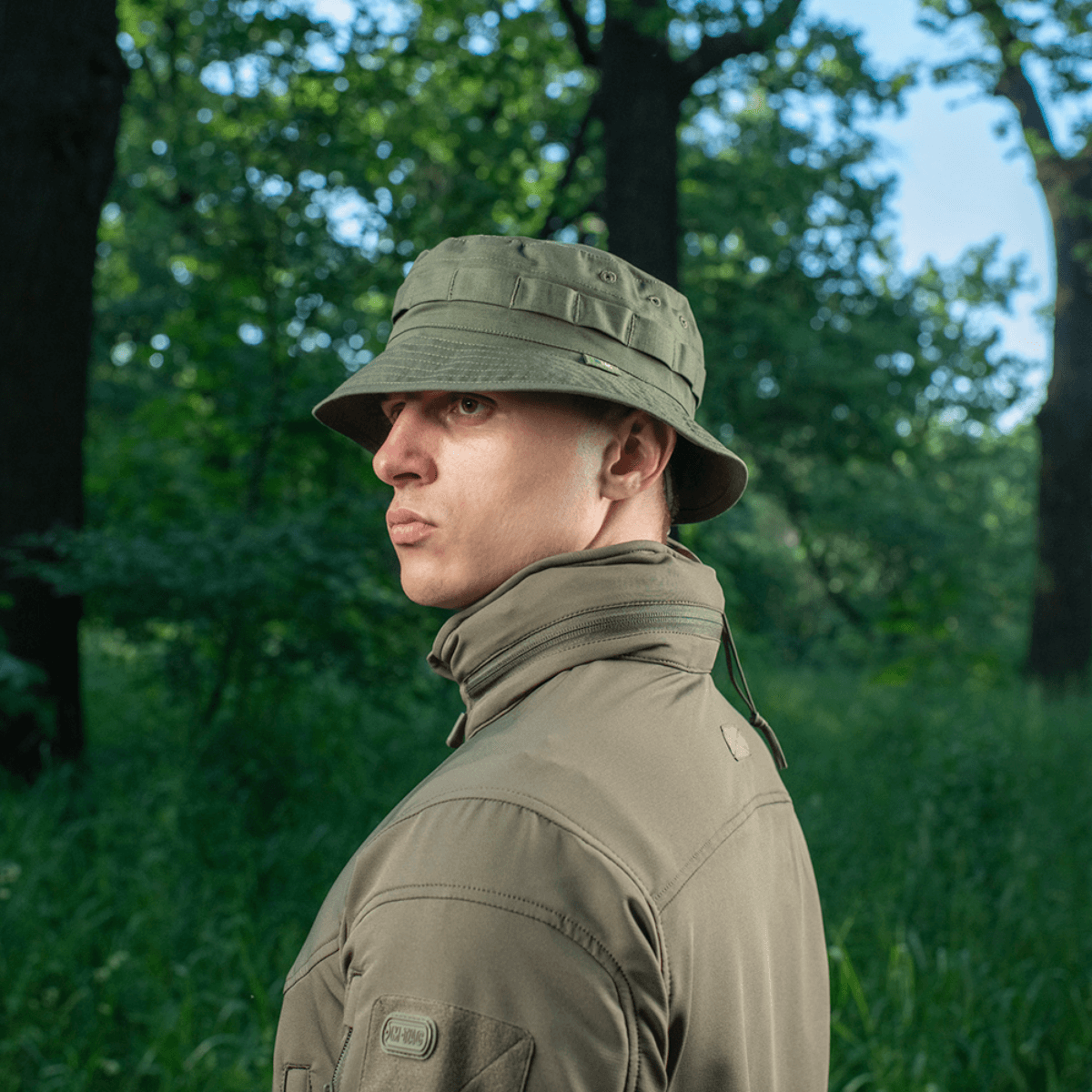 Mand iført M-Tac Panama Rip-Stop hat i skovmiljø, med ventilationshuller og camouflagestropper for optimal anvendelighed og stil.