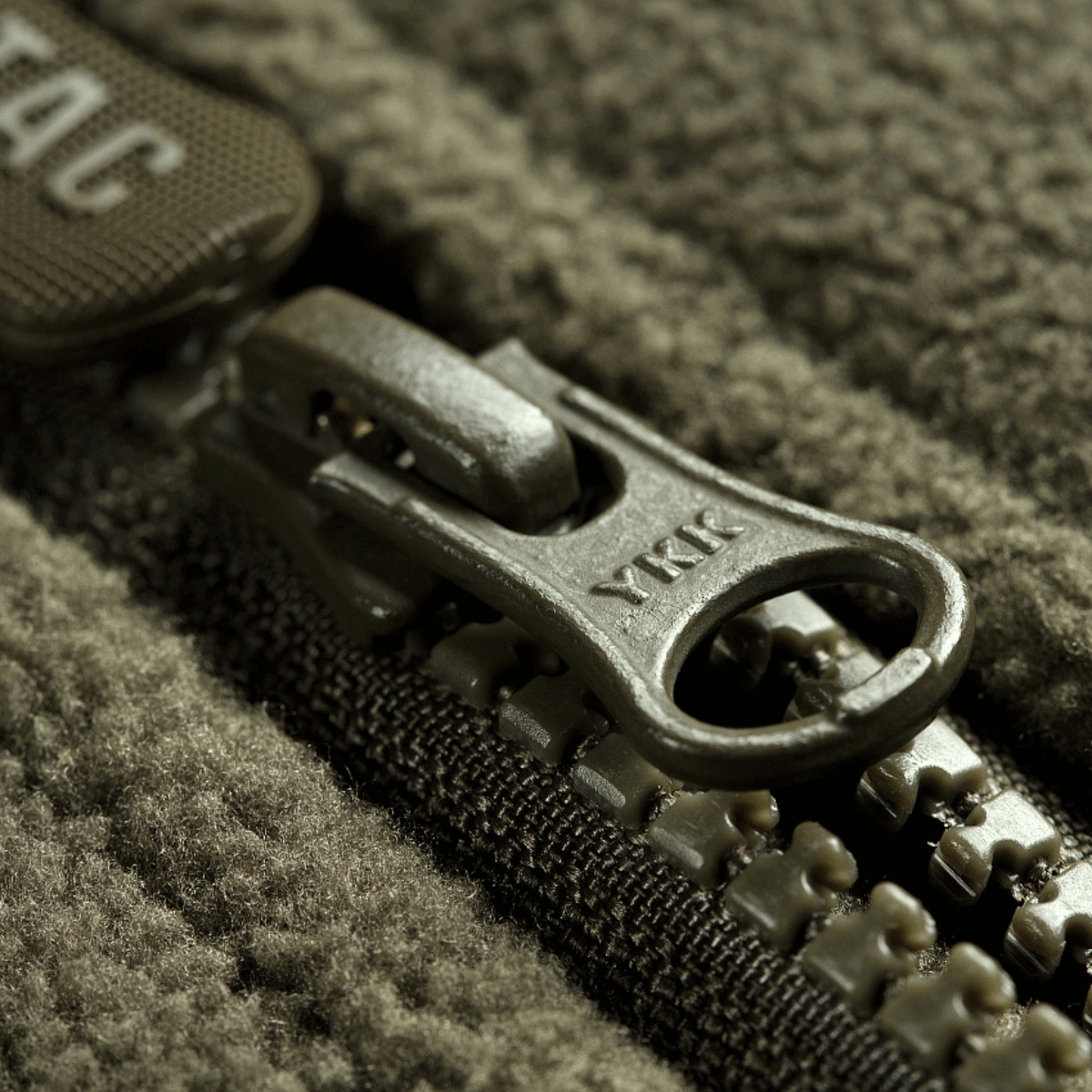 Nærbillede af lynlås på M-Tac Alpha Microfleece Jakke Gen.II, vist i forstærket fleece med ekstra slidstærke detaljer.