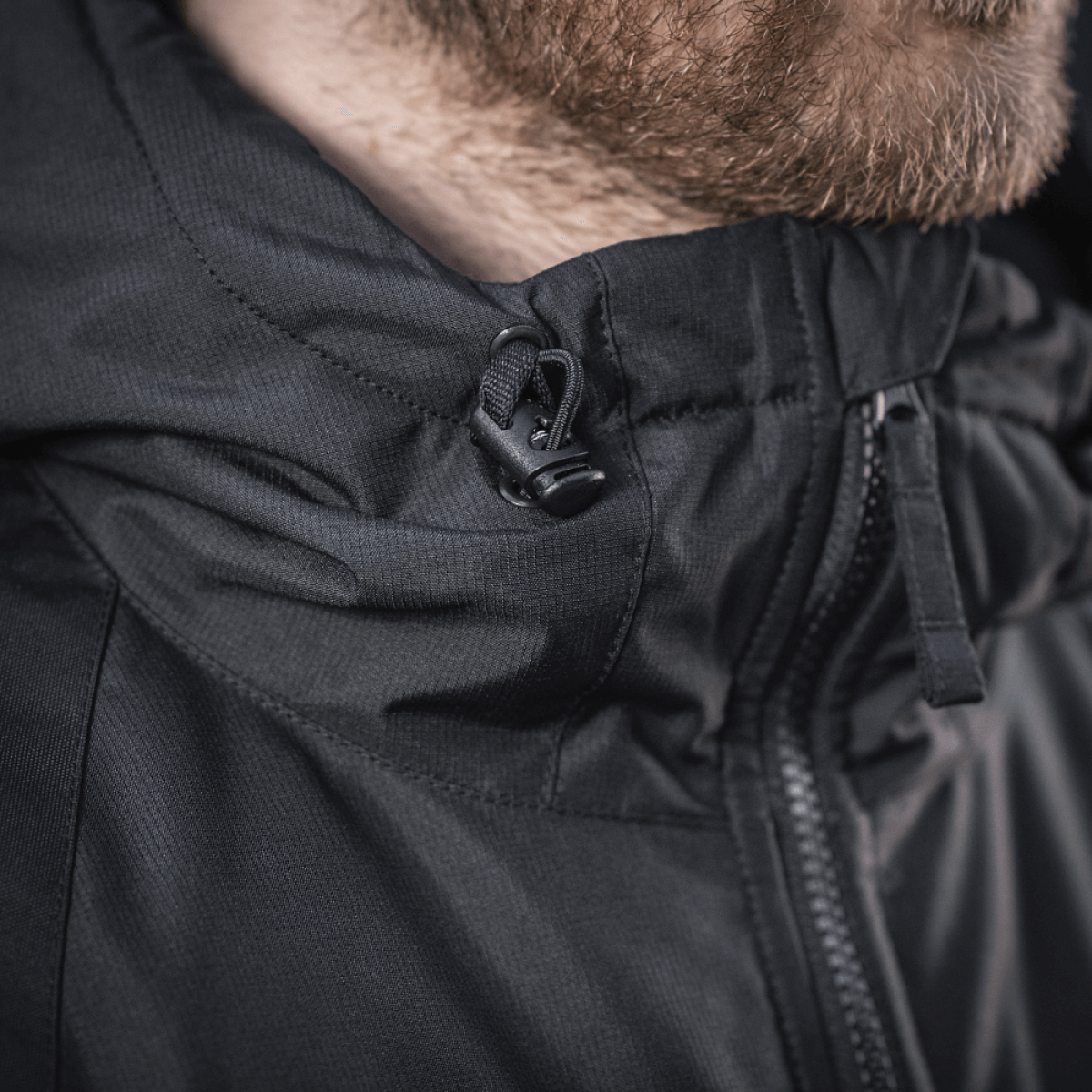 M-Tac Alpha Gen.III Pro Vinterjakke med fastsyet justerbar hætte og vandtæt nylon, tæt på lynlås og hættens snøre.