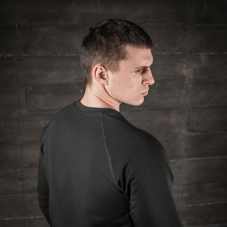 Mies pukeutuneena M-Tac Raglan Athlete -musta college raglanhihoilla, takaa nähtynä, sopii urheiluun ja arkeen.