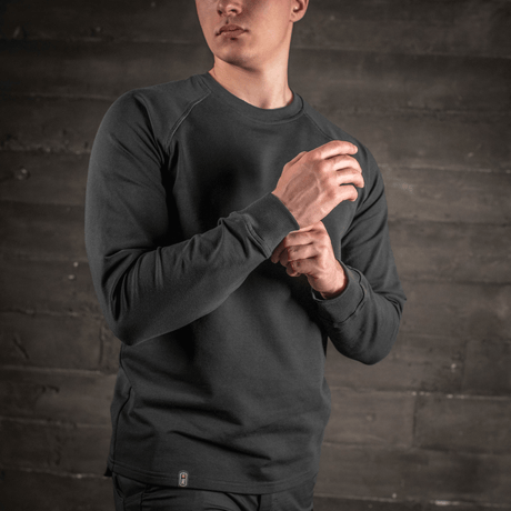 Mies pukeutuneena M-Tac Raglan Athlete -musta college pyöreällä pääntiellä ja raglanhihoilla, sopii urheiluun ja arkeen.