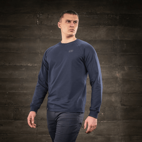 M-Tac Raglan Athlete -college minimalistisella muotoilulla ja raglanhihoilla, mallin päällä rustiikissa taustassa.
