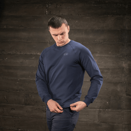 Mies pukeutuneena M-Tac Raglan Athlete -tummansininen college raglanhihoilla ja pyöreällä pääntiellä, optimaalinen liikkuvuus.