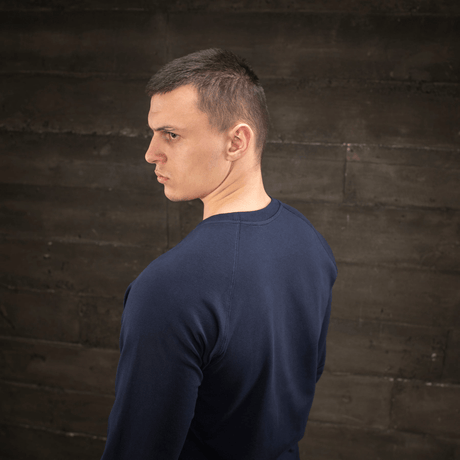Mies pukeutuneena M-Tac Raglan Athlete -laivastonsininen college pyöreällä pääntiellä ja raglanhihoilla, sivulta nähtynä, sopii urheiluun ja arkeen.