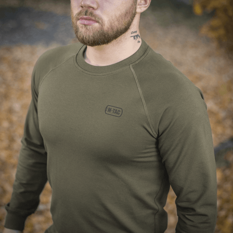 M-Tac Raglan Athlete oliivinvihreänä raglanhihoilla, sopii arkeen ja urheiluun, ulkona syksyn lehdissä.
