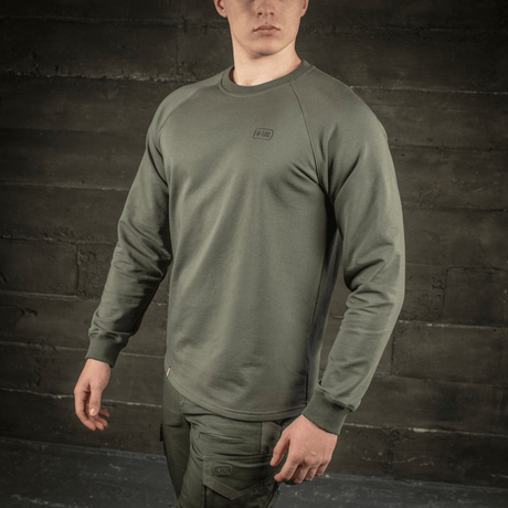 M-Tac Raglan Athlete oliivinvärisenä raglanhihoilla ja pyöreällä pääntiellä, sopii urheiluun ja arkeen, mallin päällä.