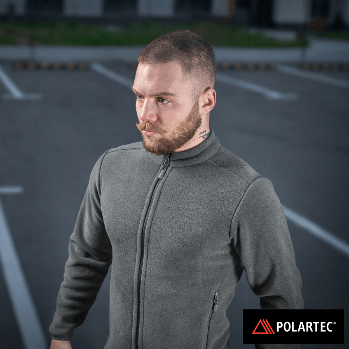 M-Tac Nord Polartec Fleecejakke i grå Polartec® 200 Series fleece, ideel til hverdag og sport, bæres af en mand på parkeringsplads.