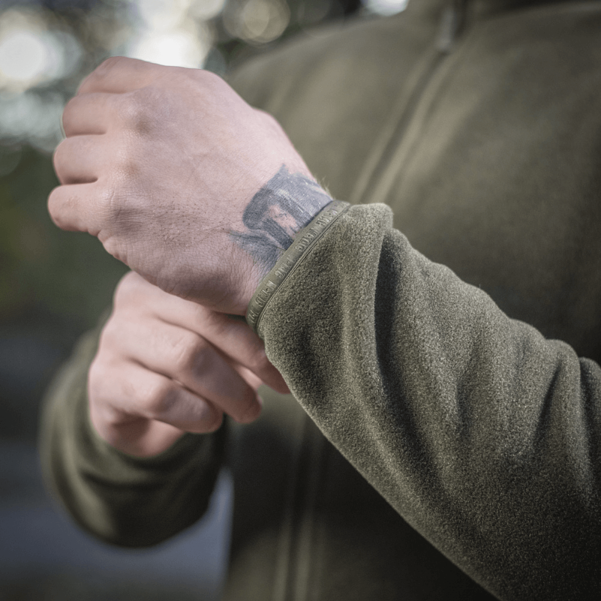 Detaljeret billede af M-Tac Nord Polartec Fleecejakke i brug udendørs, viser kvalitet og tekstur på det grønne fleece materiale.