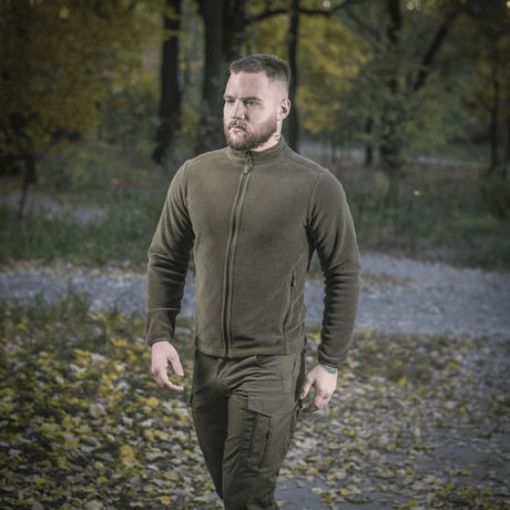 Mand iført M-Tac Nord Polartec Fleecejakke i naturen med efterårsbaggrund, viser stil, komfort og varmeisolering til hverdag og sport.