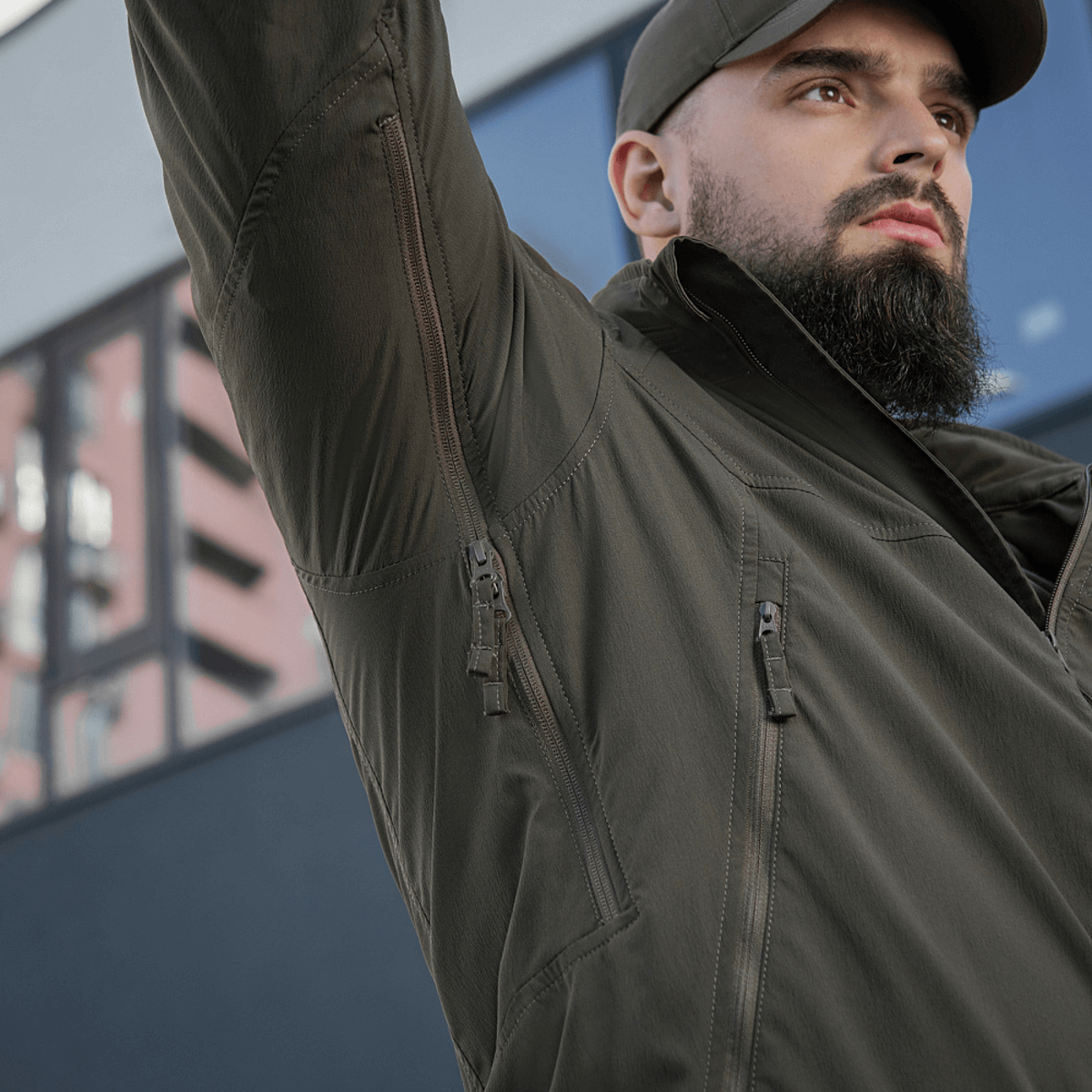 Person iført M-Tac Flash Jakke i bymiljø, let og alsidig til friluftsliv og hverdag, uden ærmevelcro, kompakt og bærbar.