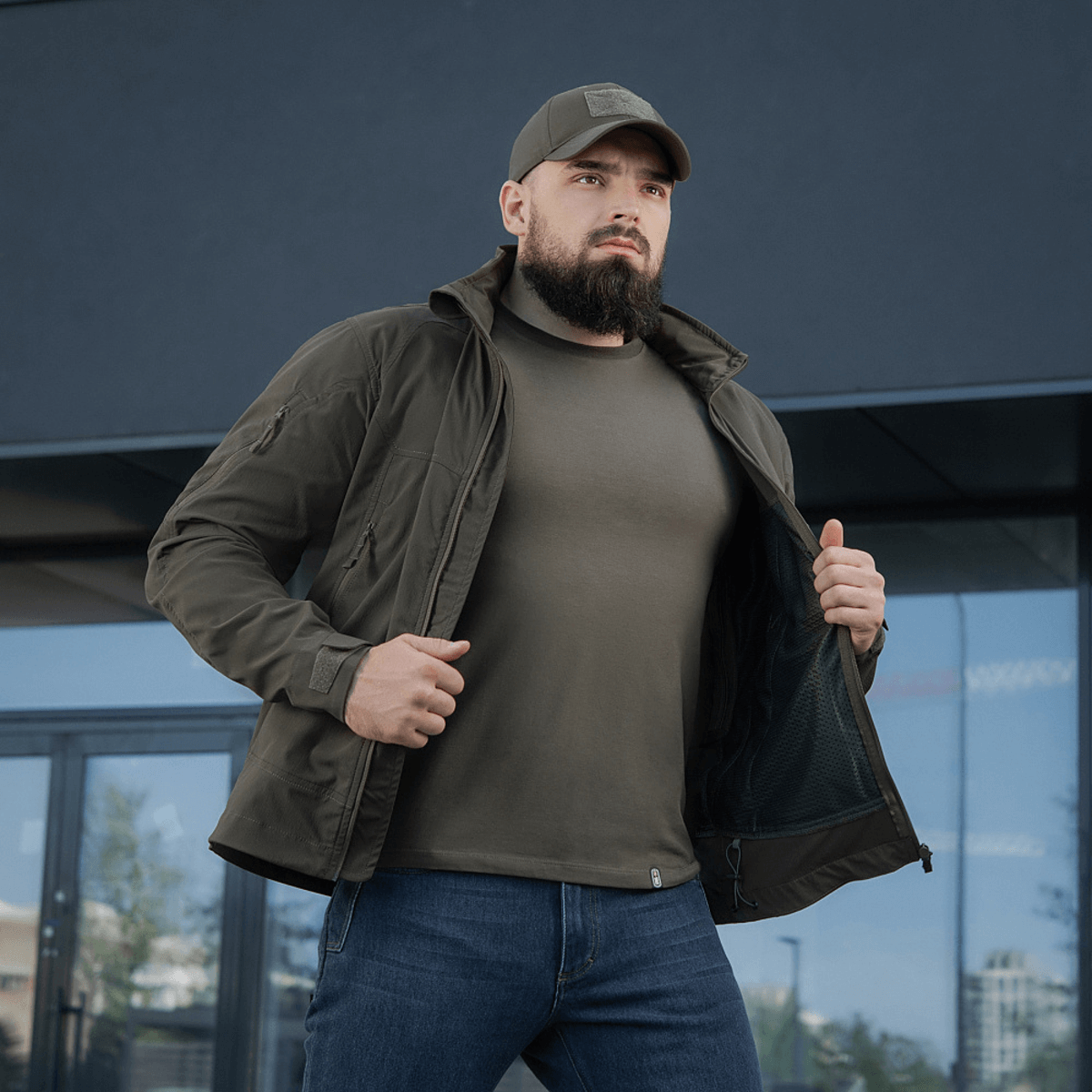 Mand iført M-Tac Flash Jakke i udendørs setting, perfekt til vandreture og sport. Let, praktisk design uden velcrofelter.