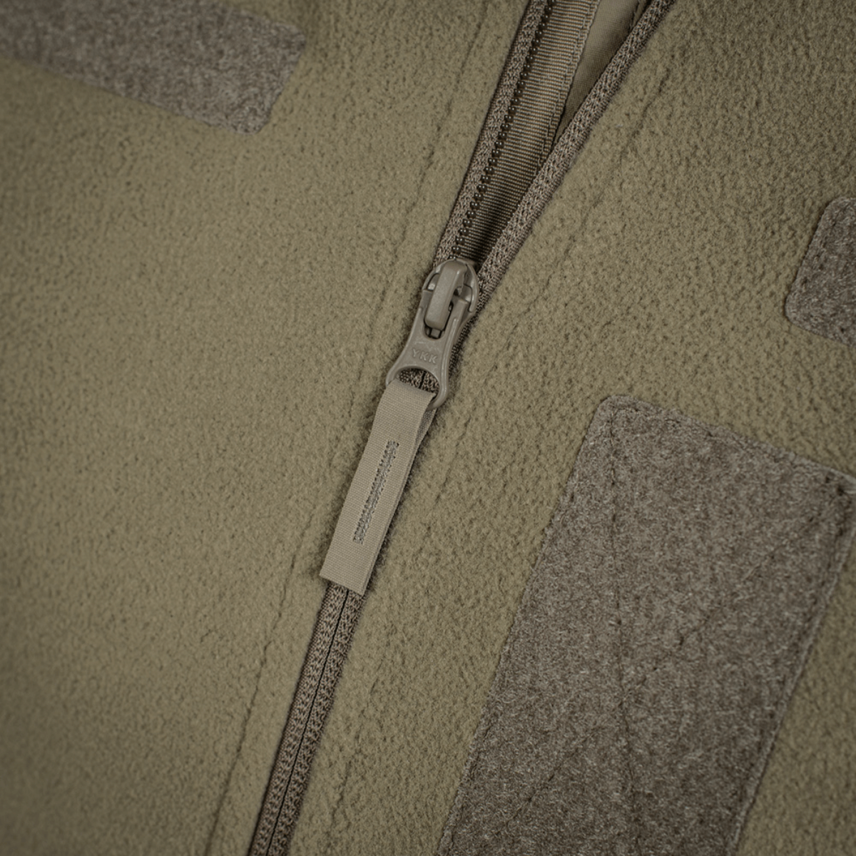 M-Tac Combat Fleece Polartec Jakke detaljeret lynlås fokus; Jakke til taktisk brug med Polartec® fleece; Grøn jakke lynlåslukning.