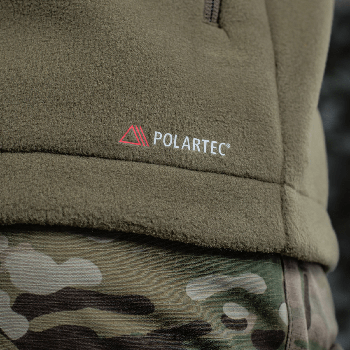 Detalje af M-Tac Combat Fleece Polartec Jakke med Polartec-logo, camouflagemønster og fleece materiale, perfekt til taktisk og casual brug.