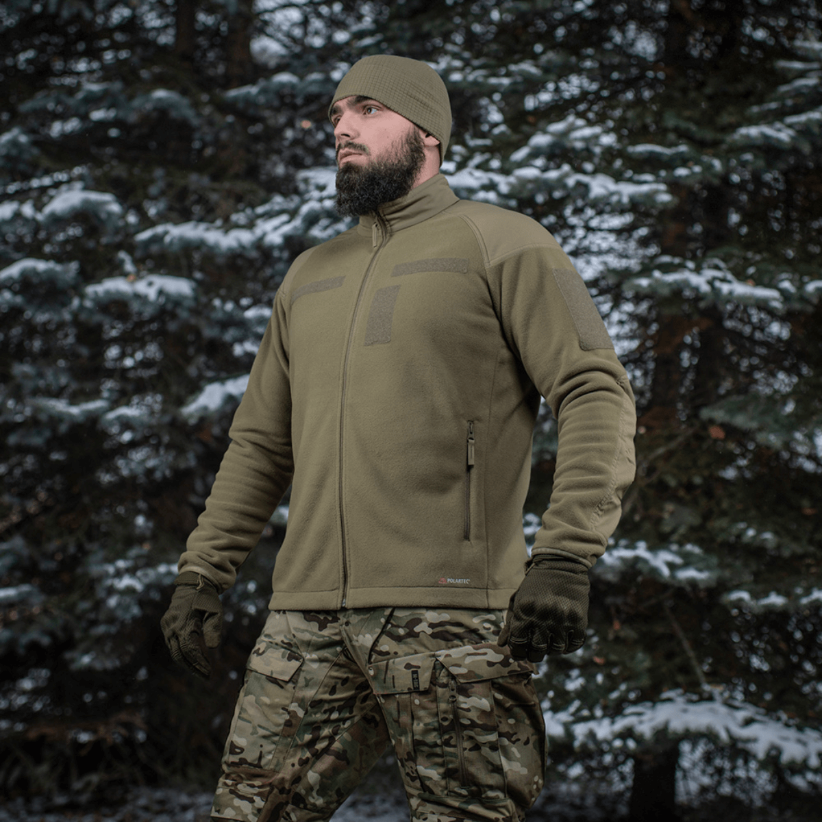 Mand iført M-Tac Combat Fleece Polartec Jakke i skovmiljø, viser jakken's funktionelle og taktiske design, ideel til udendørs brug.