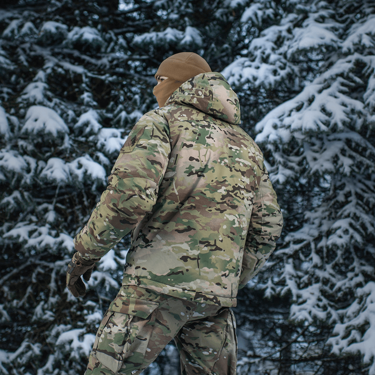 M-Tac Alpha Gen.IV Pro Primaloft Vinterjakke i snebeklædt skov med Multicam-design for ekstrem holdbarhed og koldbeskyttelse.