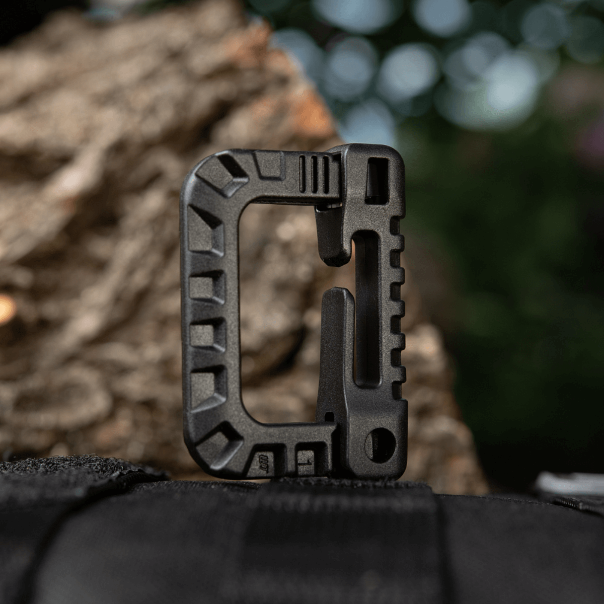 M-Tac Plast Karabin i stærkt ABS-plastik til udstyrsfæstning, tæt visning med naturbaggrund.