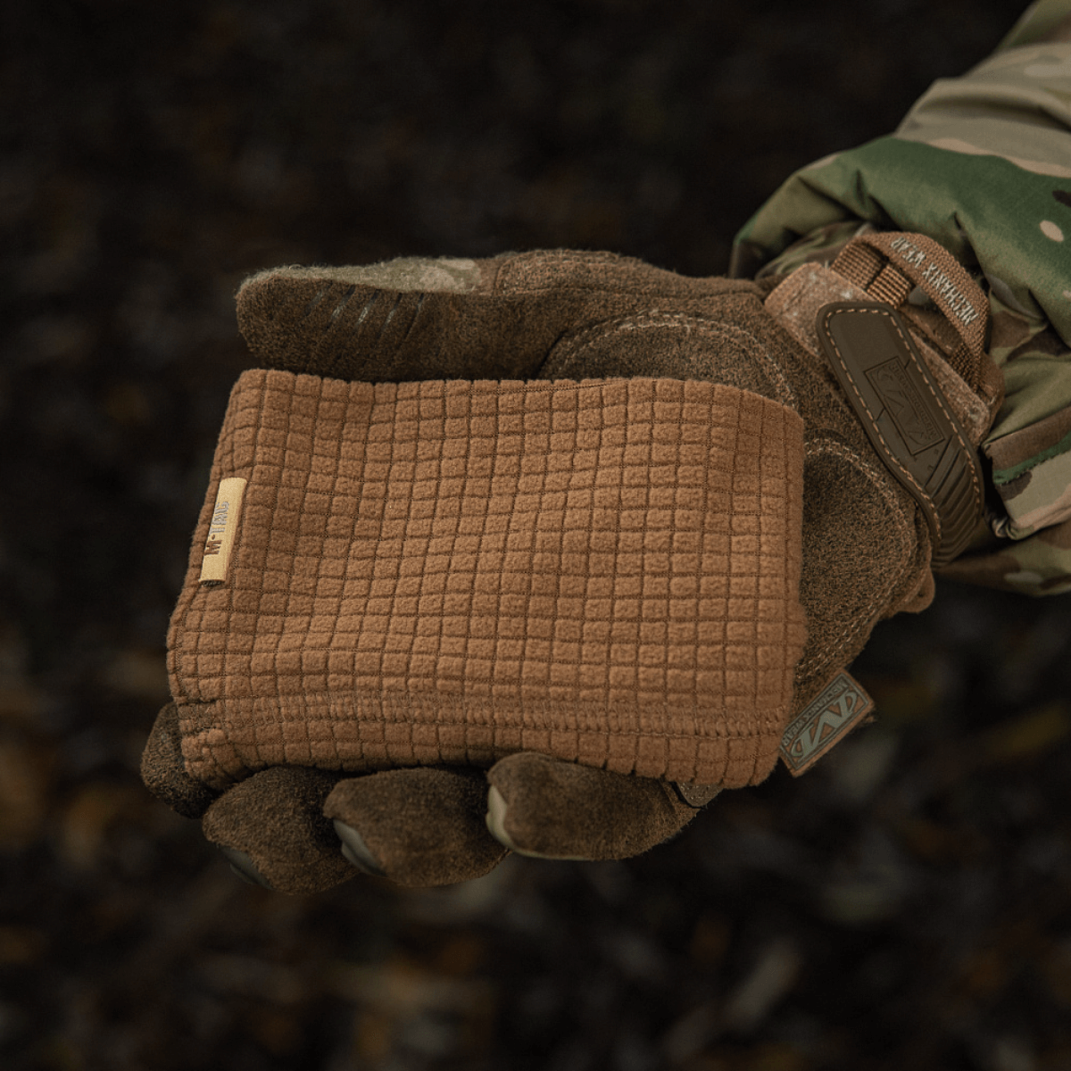 M-Tac Rip-Stop Fleece Hjelmliner i en hånd iført camouflagehandske, viser varmetekstur og holdbarhed til køligt vejr.