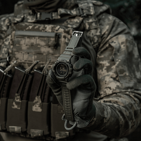 M-Tac Tactical Ur med Kompas 2233 pidetty taktisesti pukeutuneen henkilön toimesta, näyttää kestävän kellomuotoilun ulko- ja arkeen.