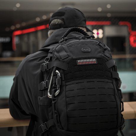 Henkilö repun kanssa, jolla on M-Tac Patch Flag 25x80 Mini Squares, Cordura 500d ja Velcro-kiinnitys, sopii taktiseen varustukseen,