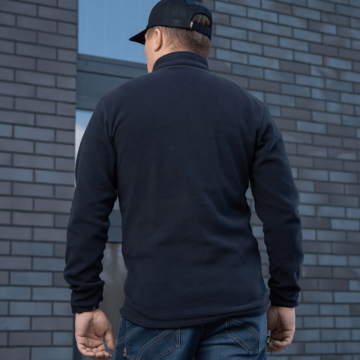 M-Tac Delta Polartec Fleecejakke set bagfra, varm og stilren jakke lavet af Polartec® Micro Series-fleece i en bymæssig baggrund.