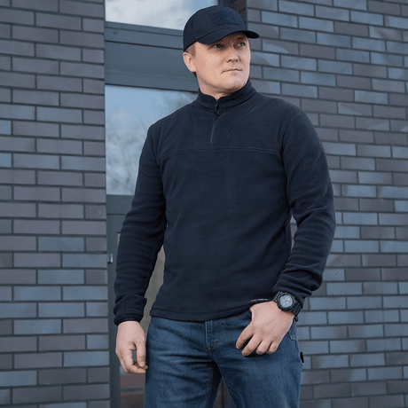 Mand iført M-Tac Delta Polartec Fleecejakke foran en murstensbygning.