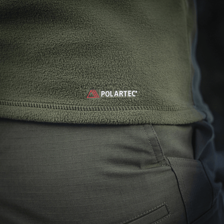 Nærbillede af M-Tac Delta Polartec Fleecejakke i olivengrøn med Polartec-logo, fremstillet af slidstærkt og åndbart Polartec® Micro Series-fleece.