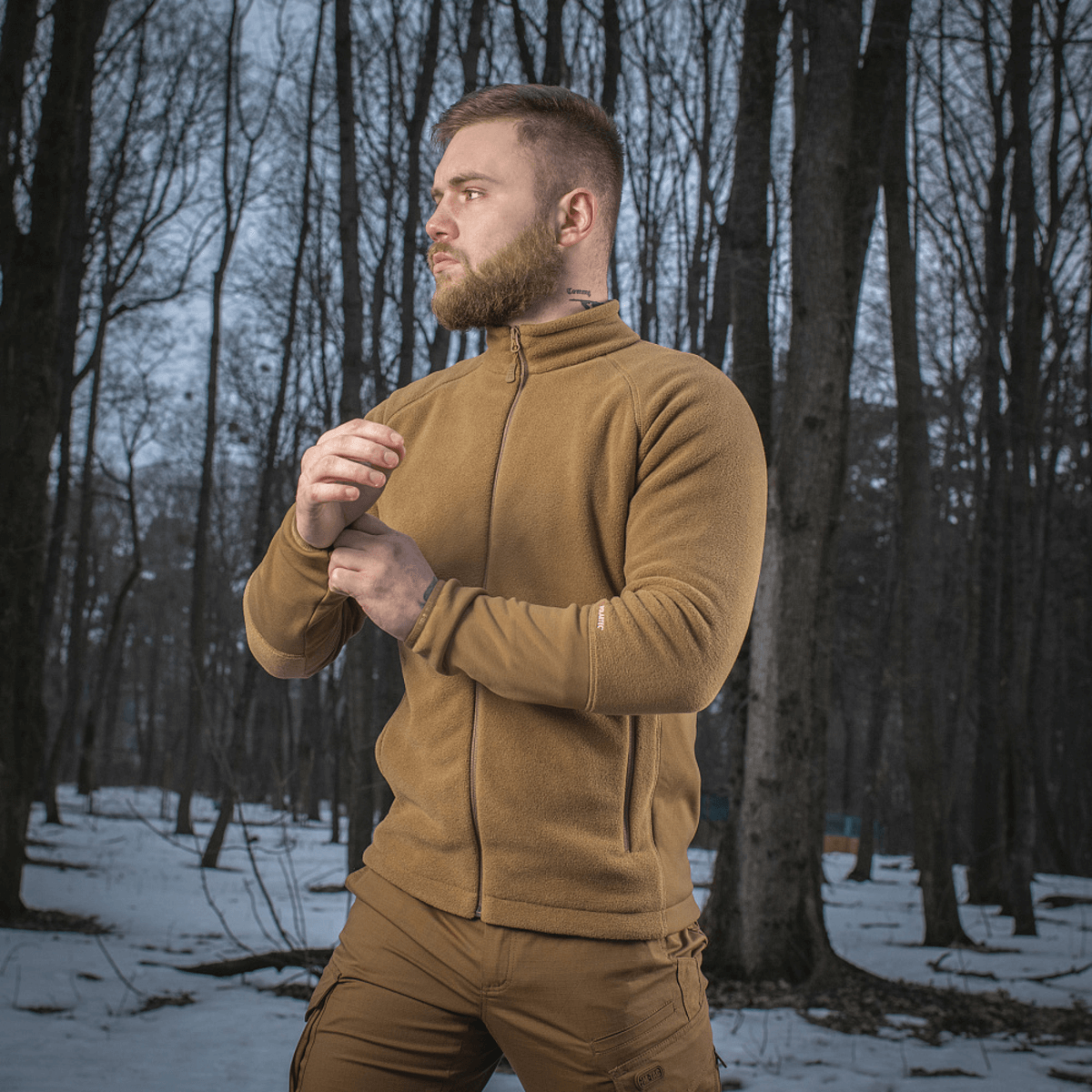 Mand iført M-Tac Polartec Sport Fleecejakke, står i skov med sne, demonstrerer jakken's komfort og funktionalitet i koldt vejr.